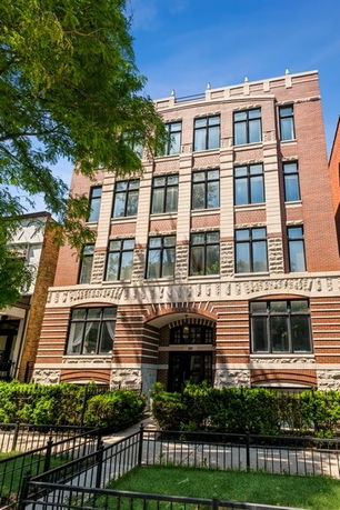 Front view of a multi-story brick building with large windows.