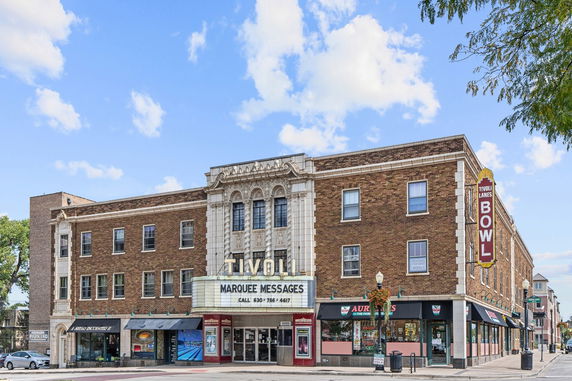 Front view of a multi-story brick building with marquee and signage.