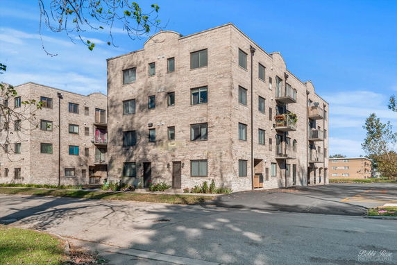 Front view of a multi-story apartment building with brick exterior and balconies.