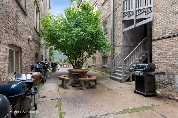 Outdoor area between brick buildings with stairs, picnic tables, and grills.