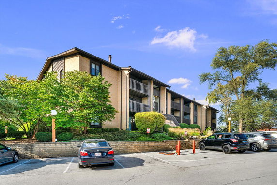 Front view of a multi-story apartment building with balconies and parking area.