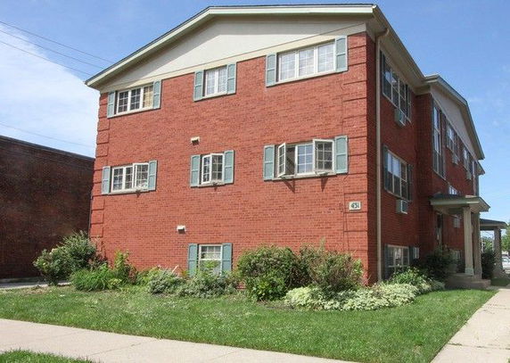 Front view of a three-story red brick building with multiple windows.