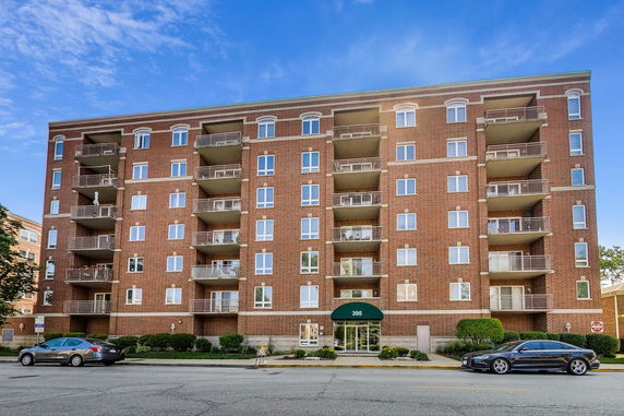 Front view of a multi-story brick apartment building with balconies.