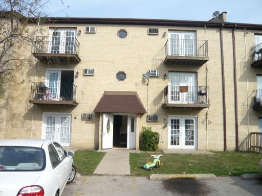 Front view of a three-story apartment building with balconies and a central entrance.