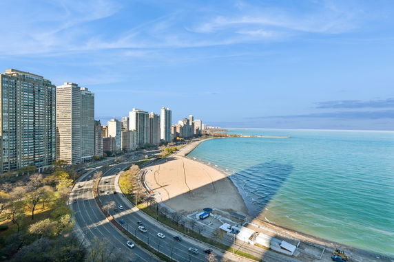 Panoramic view of high-rise buildings along a coastline with a beach and a road.