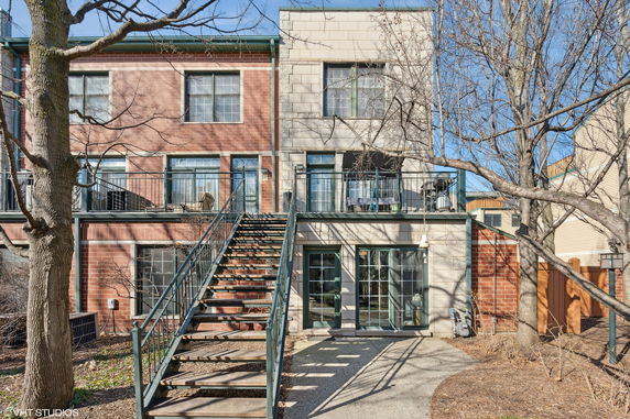 Front view of a two-story brick and stone house with outdoor stairs leading to the upper level.