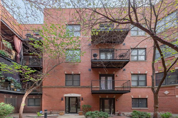 Front view of a multi-story brick apartment building with balconies.