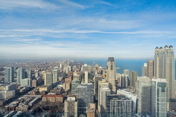 Panoramic view of a cityscape with tall buildings and a distant shoreline.