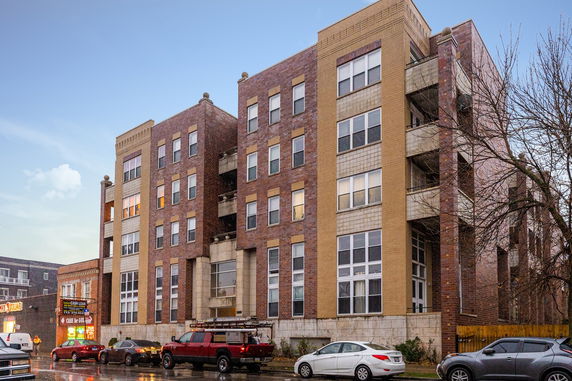 Front view of a multi-story apartment building with brick and stone façade.