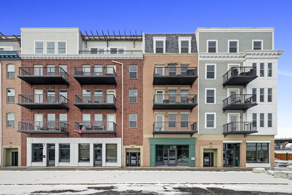 Front view of a multi-story building with multiple balconies and different facade materials.