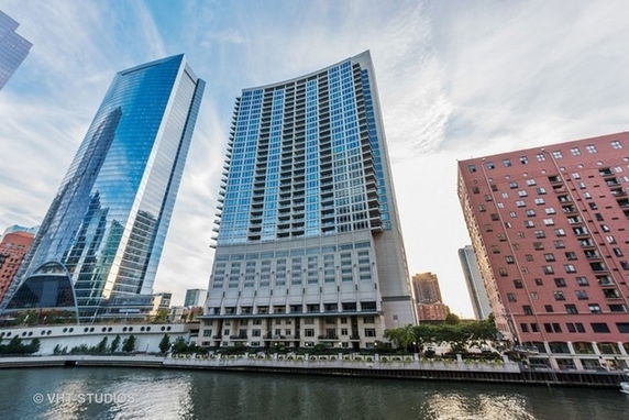 Front view of a high-rise building with glass facade near a river.