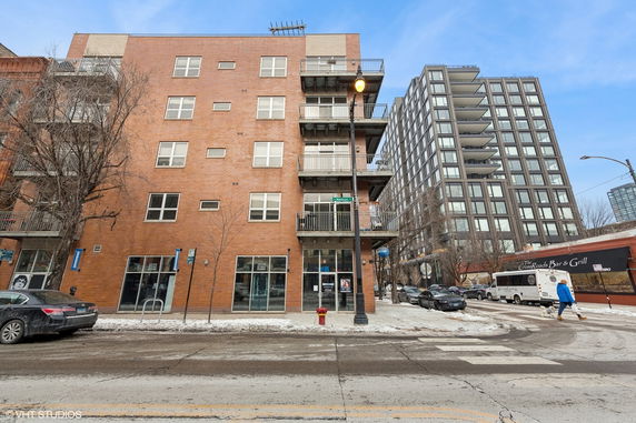 Front view of a multi-story brick building with balconies and large windows.