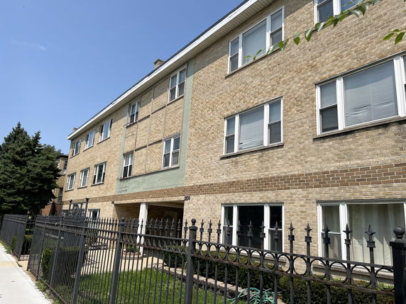 Front view of a three-story brick apartment building with multiple windows.