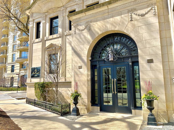 Front entrance of a stone building with decorative elements and large black double doors.
