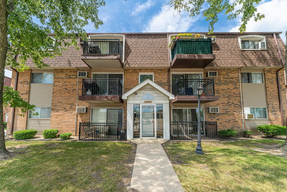Front view of a three-story apartment building with balconies and a brick facade.