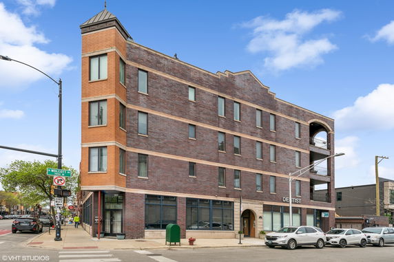 Front view of a multi-story brick building on a street corner.