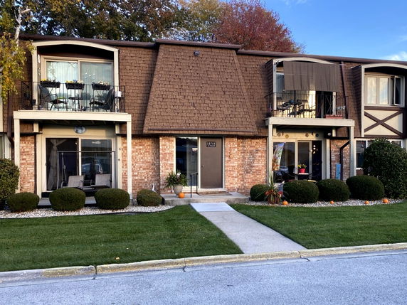 Front view of a residential building with balconies and a brick facade.
