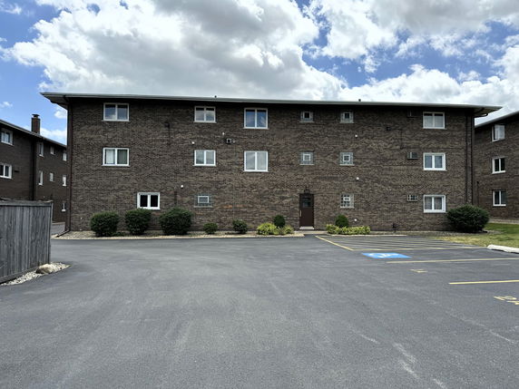 Front view of a multi-story brick building with parking area in front.