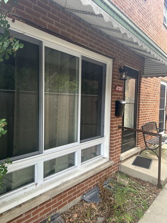 Front view of a brick house with a large window and a metal awning.