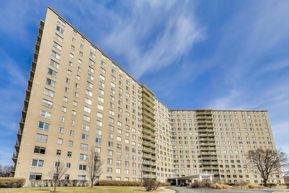 Front view of a tall apartment building with multiple floors and balconies.