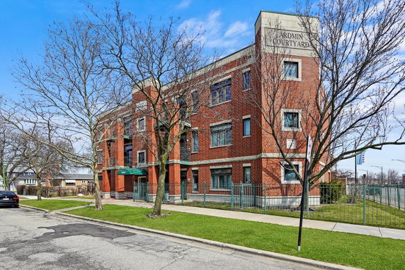 Front view of a three-story brick building with multiple windows and a gated entrance.