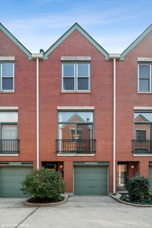 Front view of a brick townhouse with gabled roof and garage.