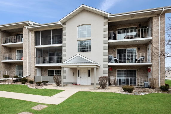Front view of a three-story apartment building with balconies and a central entrance.