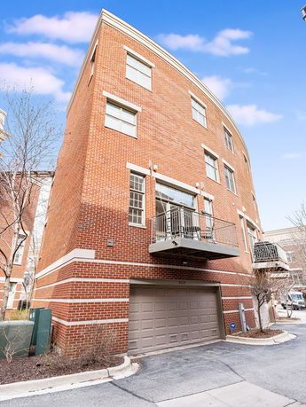 Front view of a multi-story brick building with balconies and a garage door at the base.