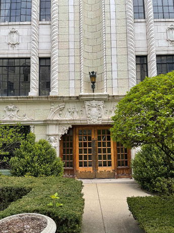 Front view of an ornate building entrance with decorative stonework and wooden double doors.