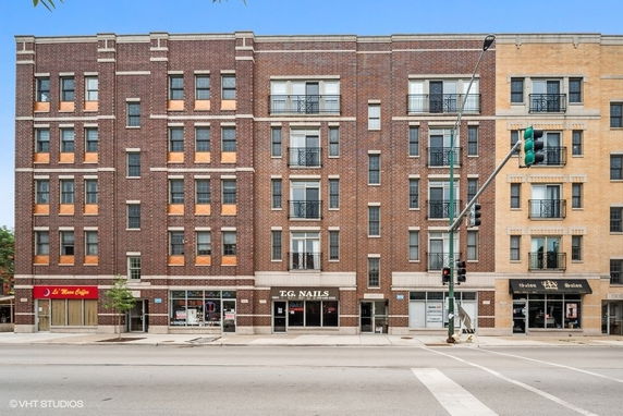 Front view of a multi-story brick commercial and residential building with shops on the ground floor.