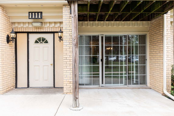 Front view of a building entrance with a door and sliding glass doors.