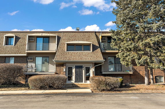 Front view of a two-story residential building with balconies and a main entrance.