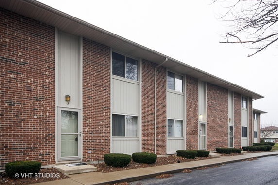 Front view of a two-story brick apartment building with multiple entrances.