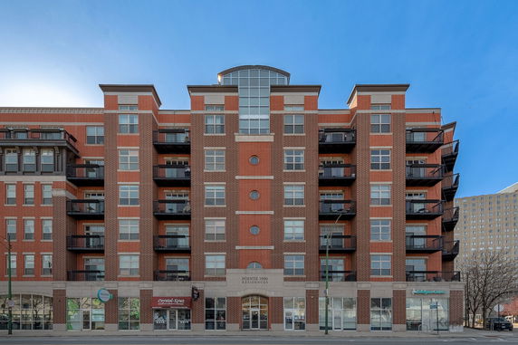Front view of a multi-story brick apartment building with balconies.