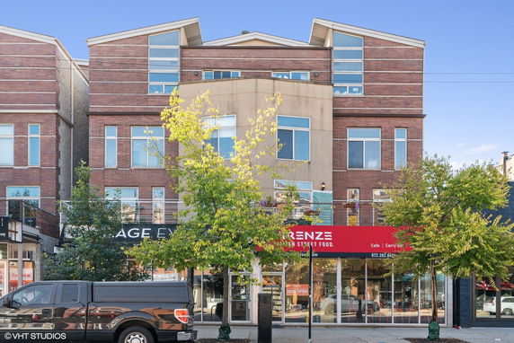 Front view of a multi-story building with brick facade and large windows.