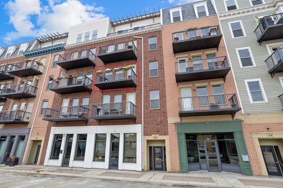 Front view of a multi-story building with multiple balconies and brick facade.