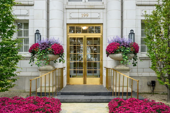 Front view of a building entrance with gold doors and decorative planters.