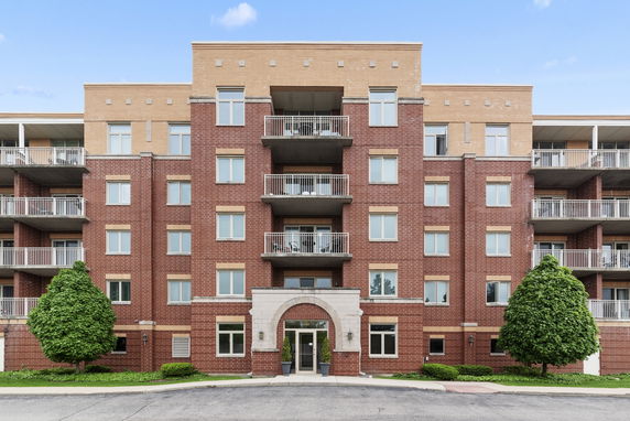 Front view of a multi-story brick apartment building with balconies.