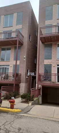 Front view of a multi-story building with balconies and large windows.