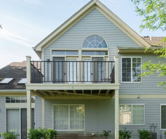 Front view of a two-story house with a balcony and large windows.