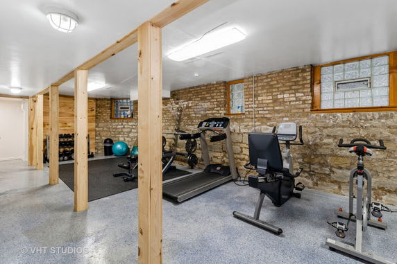 Indoor gym area with exercise equipment and a brick wall.