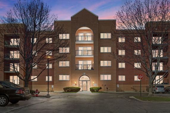 Front view of a multi-story brick apartment building with balconies.