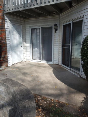 Front view of a house with a patio and sliding glass doors.