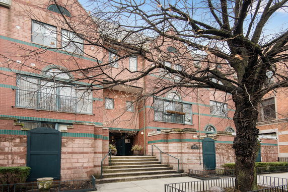 Front view of a brick apartment building with multiple windows and a central entrance staircase.