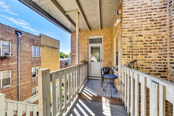 View from a building balcony showing adjacent brick buildings and a glimpse of surrounding area.