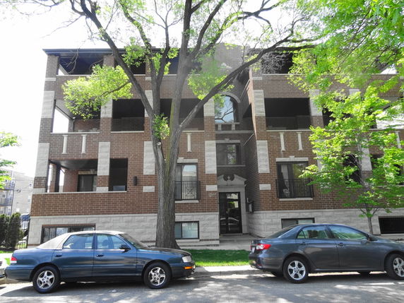 Front view of a multi-story brick apartment building with large windows and balconies.