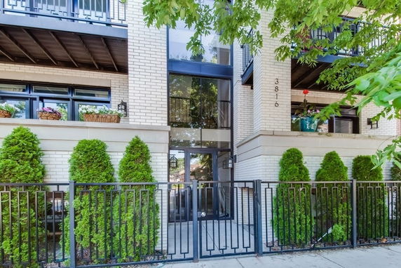 Front view of a multi-story brick building with balconies and iron fence.