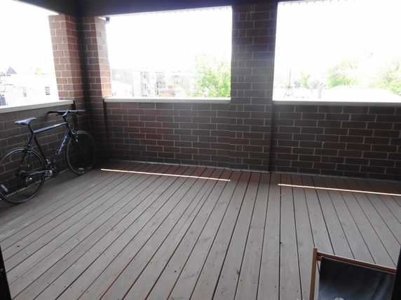 View from a brick balcony area with a bicycle and wooden flooring.