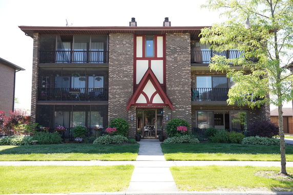 Front view of a three-story brick apartment building with balconies.