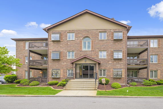 Front view of a three-story building with brick facade and multiple balconies.